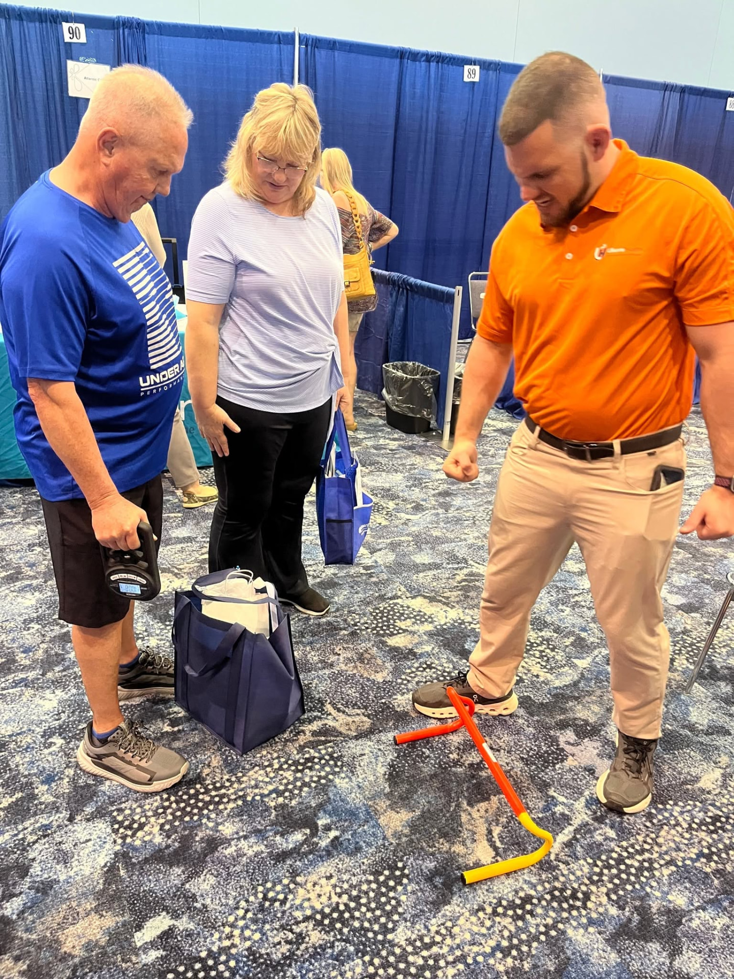 Bryan in an orange Ukemi Health shirt talking with older adults at a community wellness expo